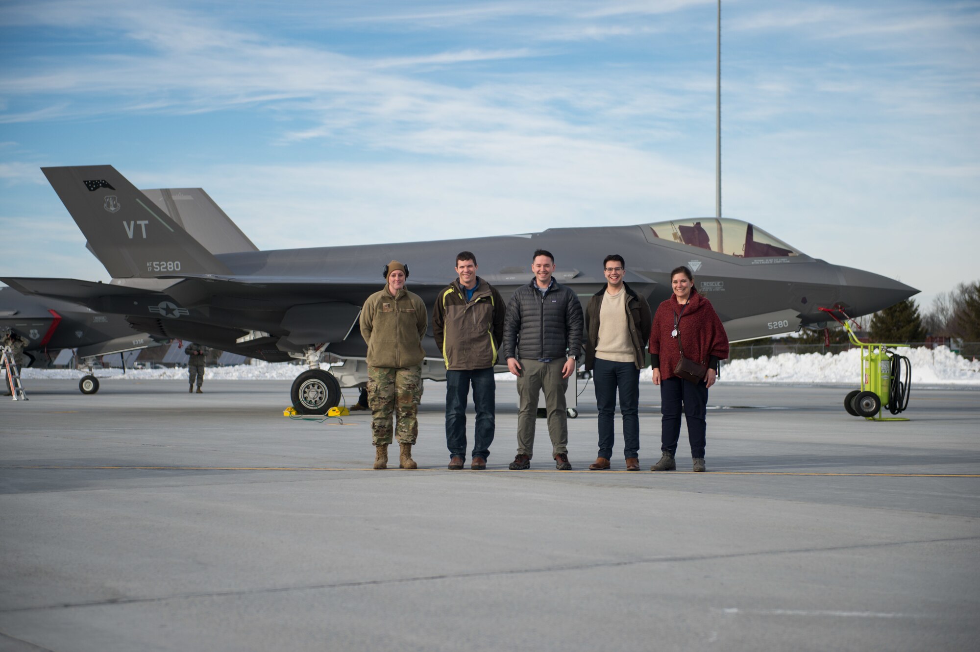 Tech. Sgt. Leah Curtin, a crew chief assigned to the 158th Maintenance Group, 158th Fighter Wing, Vermont Air National Guard, gathers together with Kessel Run employees in front of an F-35 Lightning II