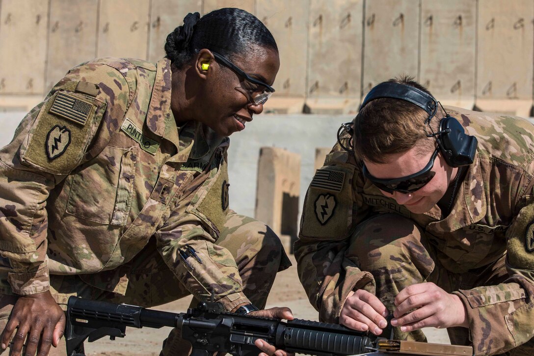 Two soldiers make adjustments on a rifle.