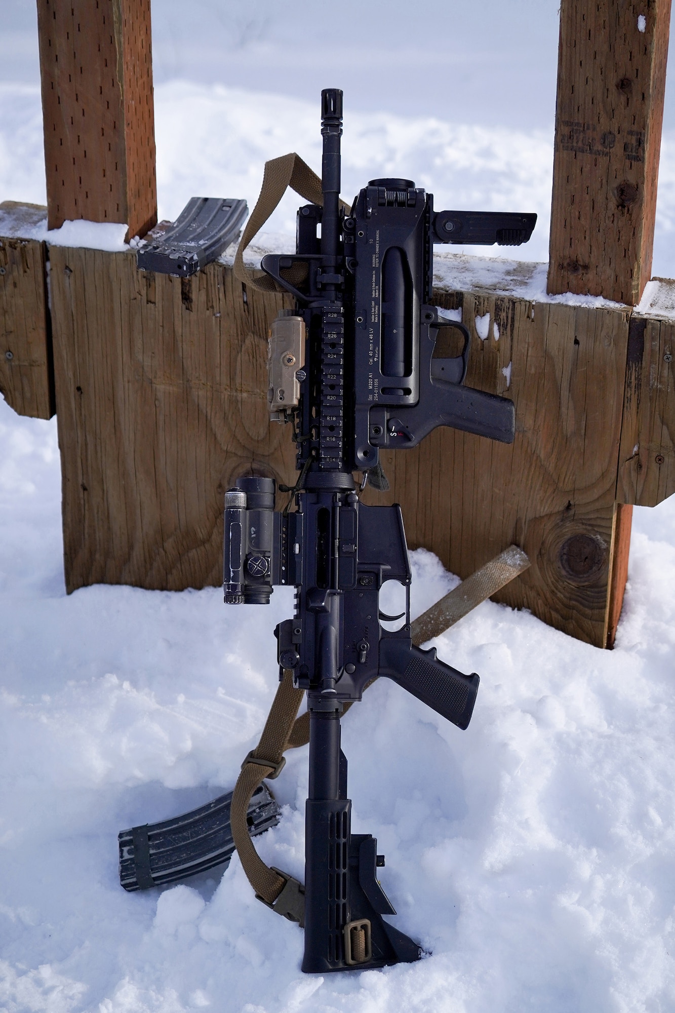 An M-4 carbine with attached M-320 40mm grenade launcher rests on a shooting platform.