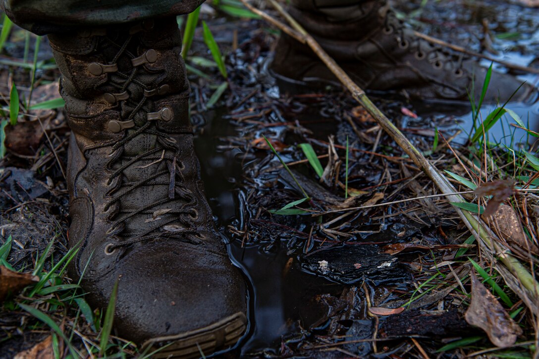 Photo of an Airman stands in mud during land navigation training.