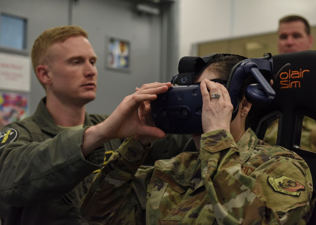 Lt. Charles Boynton, 80th Flying Training Wing Spark Cell project manager, assists Brig. Gen. Alice Trevino, Air Force Installation Contracting Center commander, with putting on virtual reality goggles at Sheppard Air Force Base, Texas, March 4, 2020. Student pilots use the virtual reality system to prepare themsleves for flight training missions as well as familiarization with flight controls. (U.S. Air Force photo by Senior Airman Ilyana A. Escalona