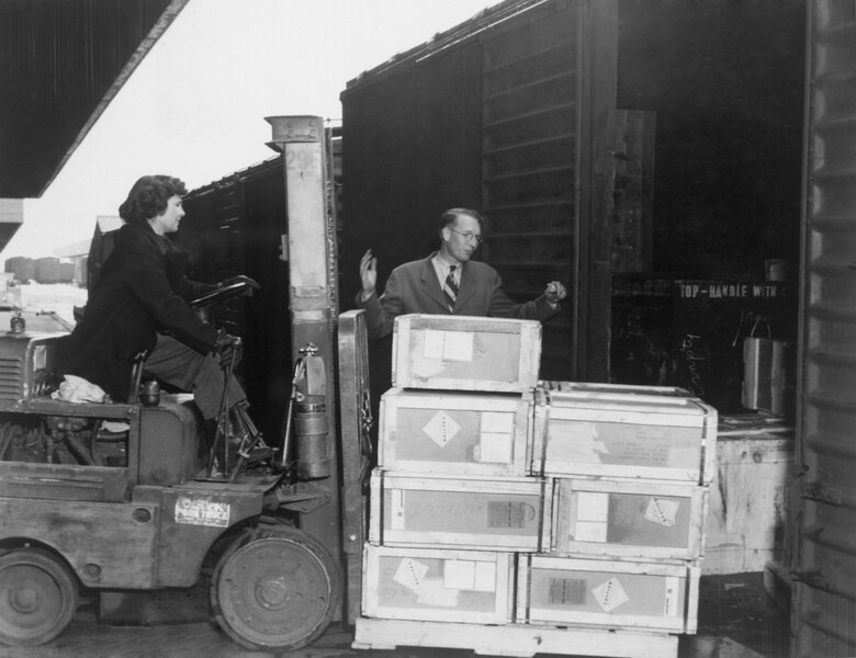 A woman loads munitions during WWII into a train car at Ogden Arsenal warehouse, part of what is now the 1200-series buildings of Hill AFB’s west area.
