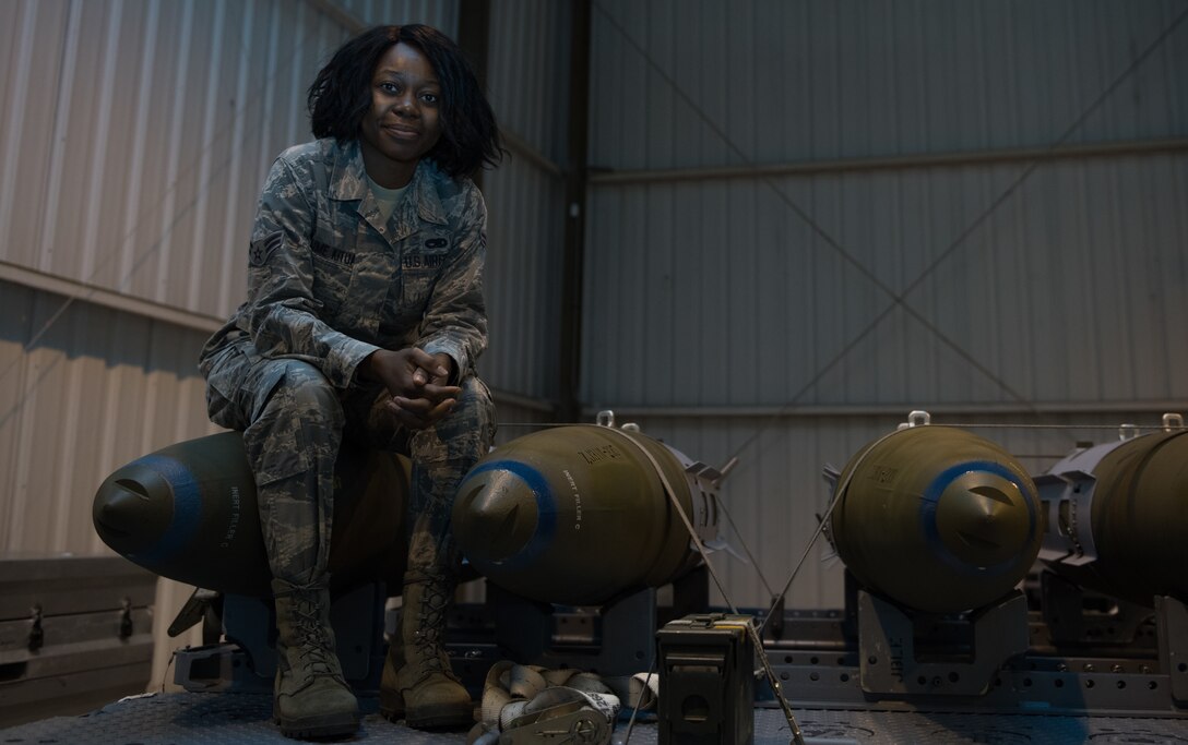 U.S. Air Force Airman 1st Class Michaelange Kalimanton Kitua, 1st Maintenance Squadron tech member, sits on top of trailer carrying demonstration bombs in the ammunitions facility at Joint Base Langley-Eustis, Virginia, Feb. 28, 2020. Kalimanton Kitua is responsible for packing and repacking ammunition and flares. (U.S. Air Force photo by Airman 1st Class Sarah Dowe)