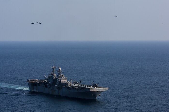 U.S. Marine Corps AV-8B Harriers fly over the amphibious assault ship USS Bataan (LHD 5) beside a Dassault Mirage 2000-5 fighter interceptor.