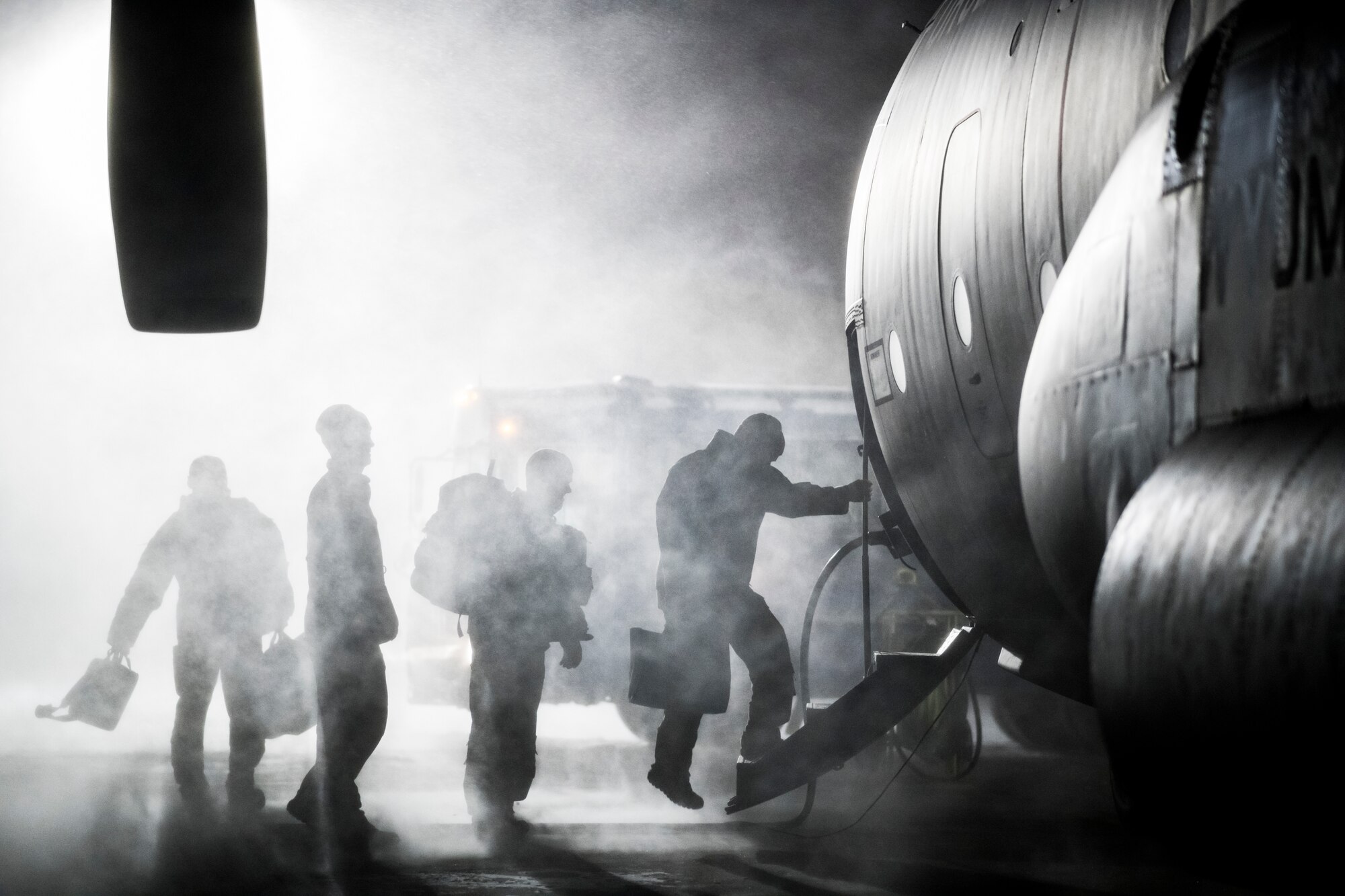 Airmen carry gear onto a C-130 Hercules for an early-morning departure