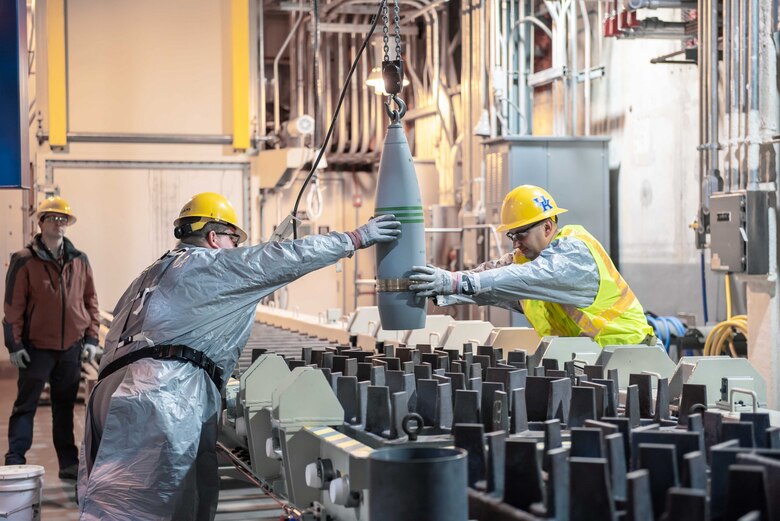 Blue Grass Chemical Agent-Destruction Pilot Plant workers place the first 8-inch projectile containing GB nerve agent in a tray to begin the destruction process in the Munitions Demilitarization Building in Richmond, Kentucky, Jan. 16, 2020.