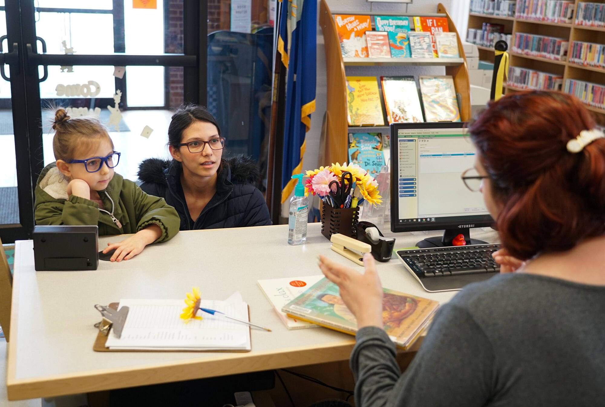 Liz Green, base resident, and her daughter Emma Green, 5, talk with a staff member March 4, 2020, in the library on Grand Forks Air Force Base, N.D. The Greens were among a small crowd who visited the library to celebrate its grand re-opening, following a six-month renovation period. (U.S. Air Force photo by Senior Airman Elora J. McCutcheon)