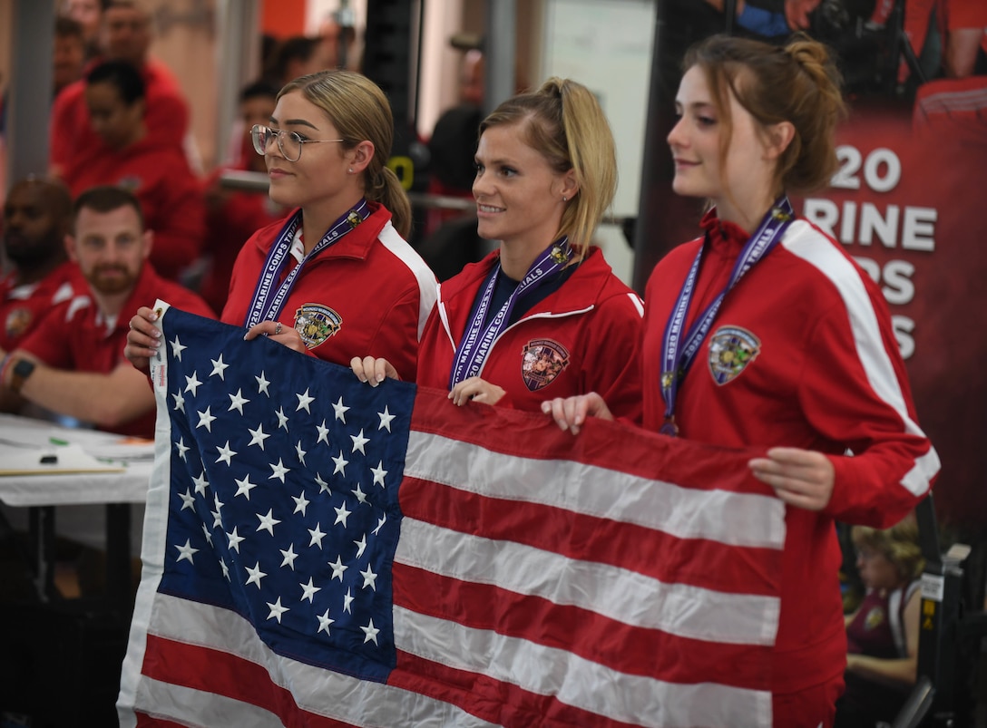 U.S. Marine Corps athletes Clair Morrow (left), Sasha Savage (middle), and Kathryn Fisher (right) hold up the American flag after medalling at the 2020 Marine Corps Trials powerlifting competition at Marine Corps Base Camp Pendleton, Calif., March 4. The Marine Corps Trials is an adaptive sports event involving more than 200 wounded, ill or injured Marines, Sailors, veterans and international competitors.