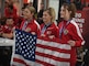 U.S. Marine Corps athletes Clair Morrow (left), Sasha Savage (middle), and Kathryn Fisher (right) hold up the American flag after medalling at the 2020 Marine Corps Trials powerlifting competition at Marine Corps Base Camp Pendleton, Calif., March 4. The Marine Corps Trials is an adaptive sports event involving more than 200 wounded, ill or injured Marines, Sailors, veterans and international competitors.