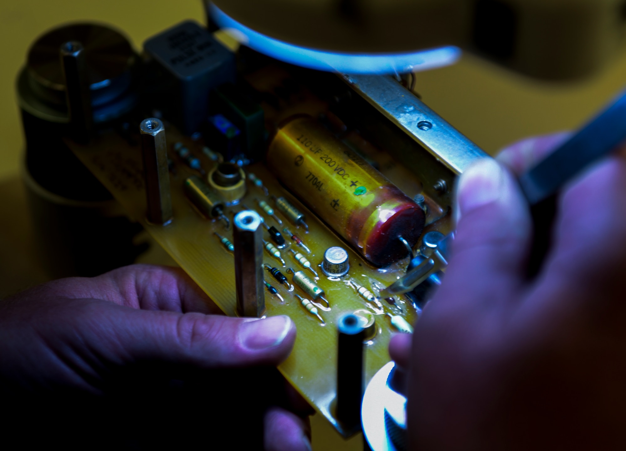 Technician uses a scalpel to cut into the protective coating of a component at Beale Air Force Base
