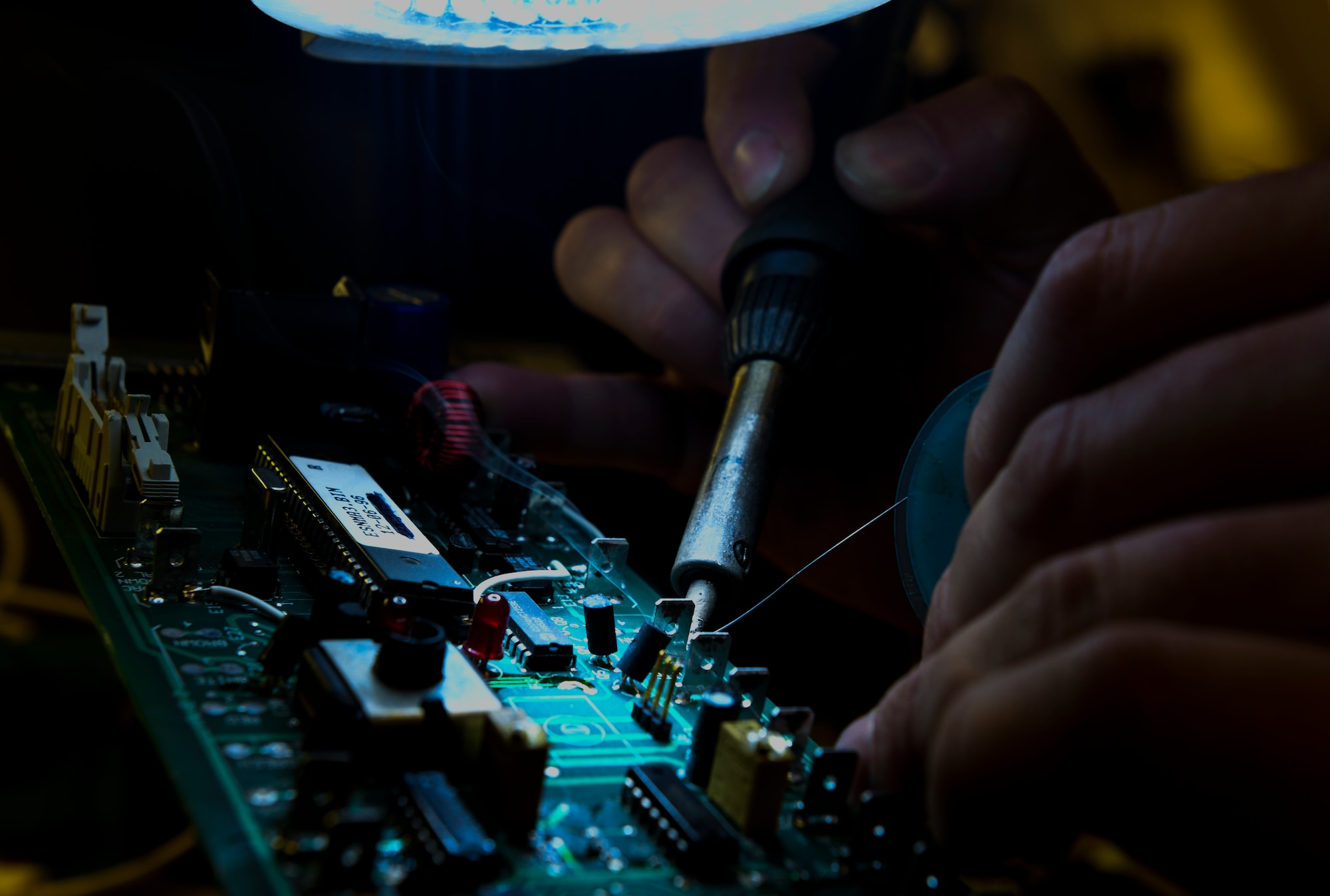 Technician works on a circuit board by soldering components at Beale Air Force Base.