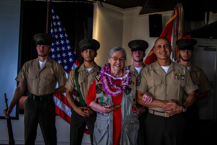 Mrs. Barbara Mathews, U.S. Marine Corps 1st Sgt. Erick Velez, Weapons Company first sergeant, 1st Battalion, 3rd Marine Regiment, and the 3rd Marine Regiment color guard pose for a group photo during an Honorary Marine ceremony, Marine Corps Base Hawaii, March 6, 2020. The Honorary Marine title is designed to reinforce the special bond between the American people and the Marine Corps by recognizing individuals in the civilian community who have made extraordinary contributions to the Marine Corps. Mrs. Mathews earns this prestigious honor for volunteering over 10 years of her personal time, talents and money capturing photo and video of hundreds of Marine Corps ceremonies, including memorials and special events surrounding the wars in Iraq and Afghanistan. (U.S. Marine Corps photo by Cpl. Matthew Kirk)