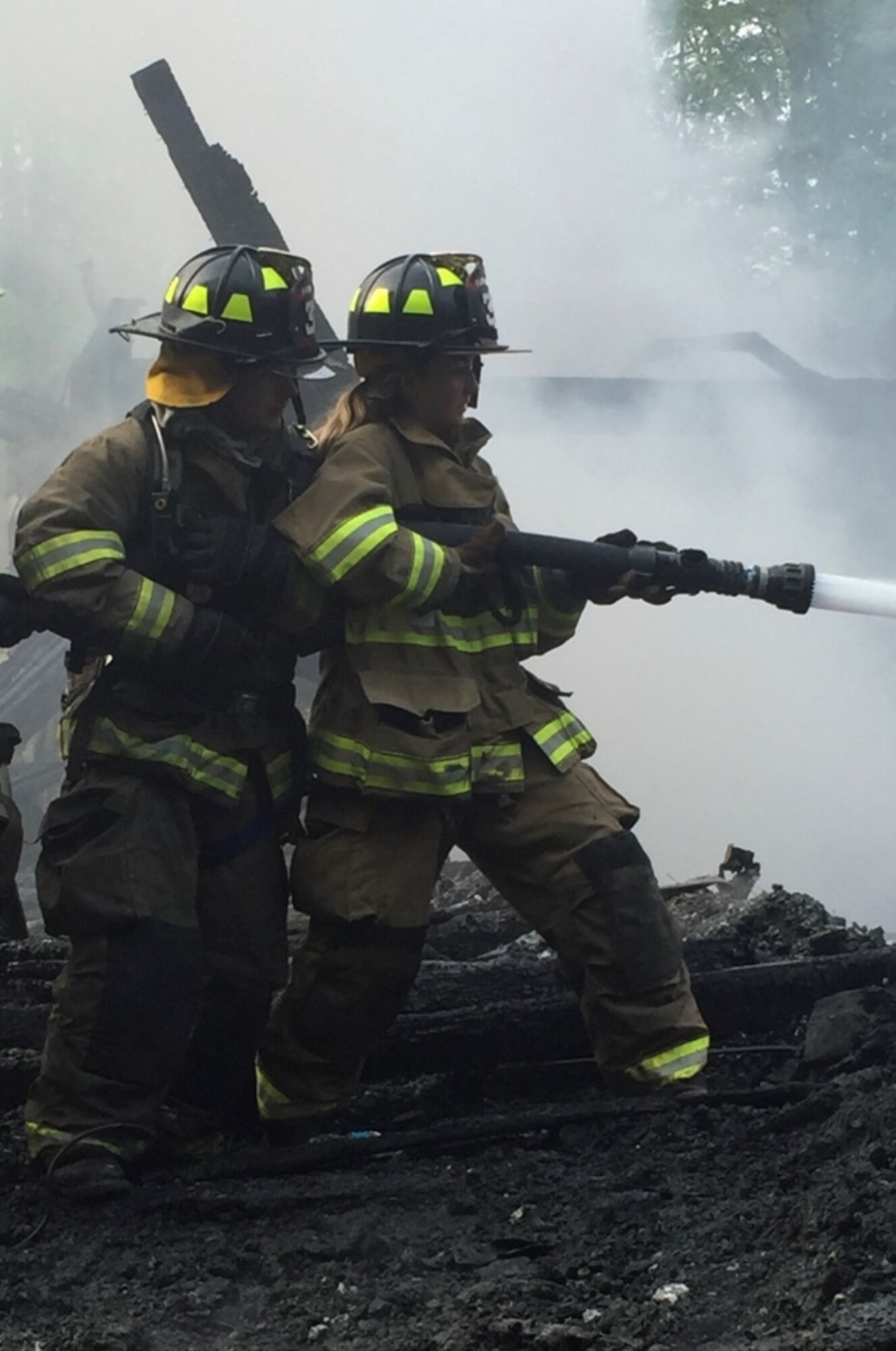 Airman 1st Class Sinéad Brosnan, 27th Special Operations Health Care Operations Squadron aerospace medical technician, uses a fire hose to put out the embers of a fire in Florida, New York, in 2016. Originally Brosnan was a volunteer EMT but began volunteering as a firefighter when New York state passed a law requiring certification to be an EMT. (Courtesy Photo)