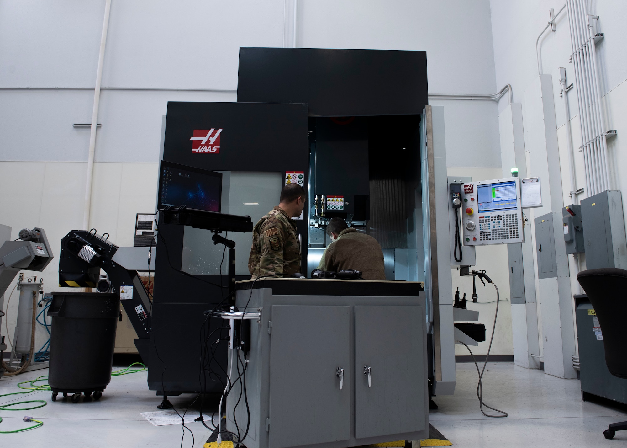 U.S. Air Force Tech. Sgt. Kevin Collins, 366th Maintenance Squadron aircraft metals technology section chief and U.S. Air Force Airman 1st Class Luke Haener, 366th MXS aircraft metals technology craftsman stand in front of a metal cutting or CNC machine, March 2, 2019, at Mountain Home Air Force Base, Idaho. The HandyScan sends the 3D image to the computer that then sends it to the CNC machine. (U.S. Air Force photo by Airman Natalie Rubenak)