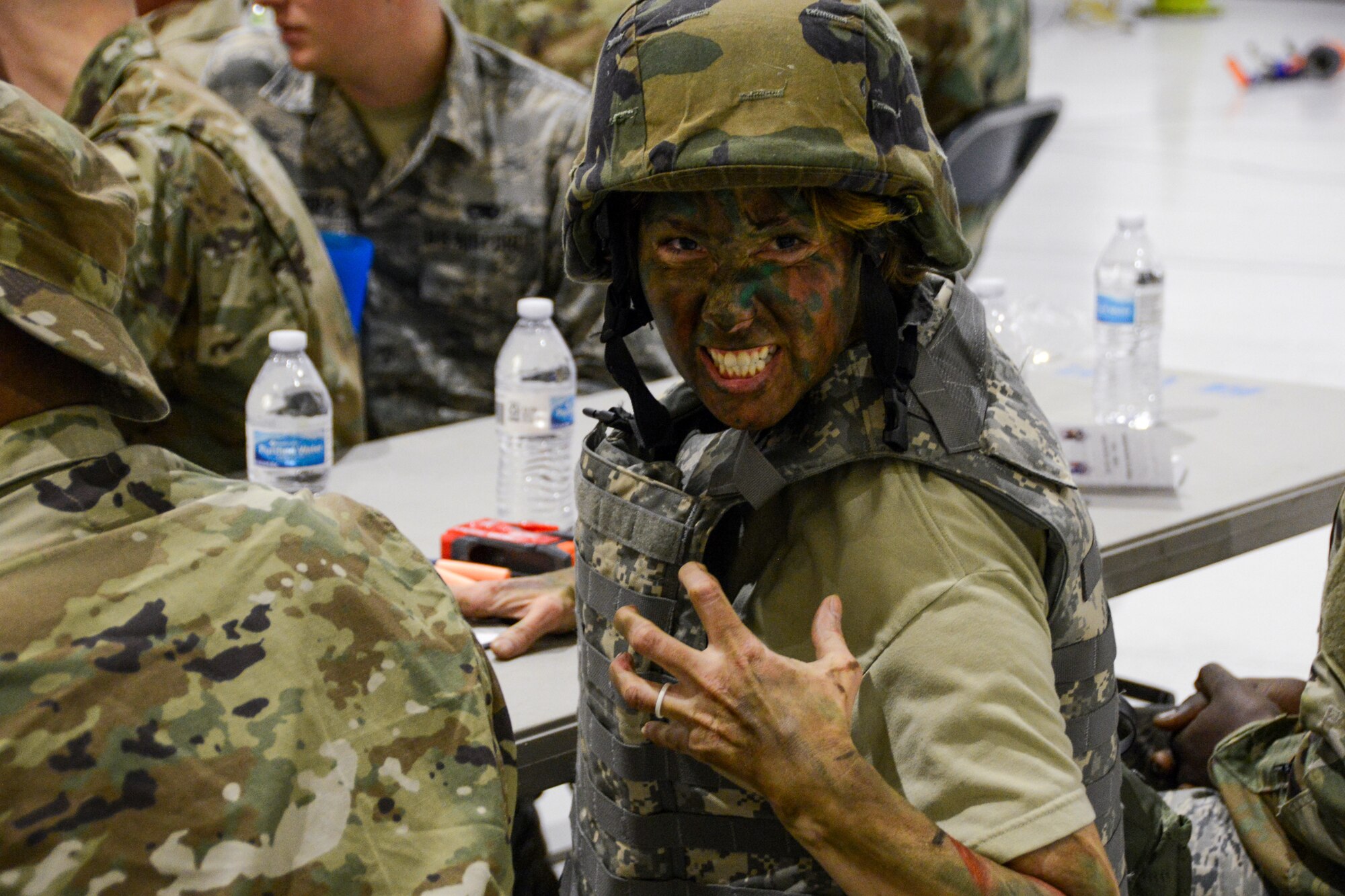 A Texas Air National Guard Airman in camouflage paint bares her teeth toward the camera.