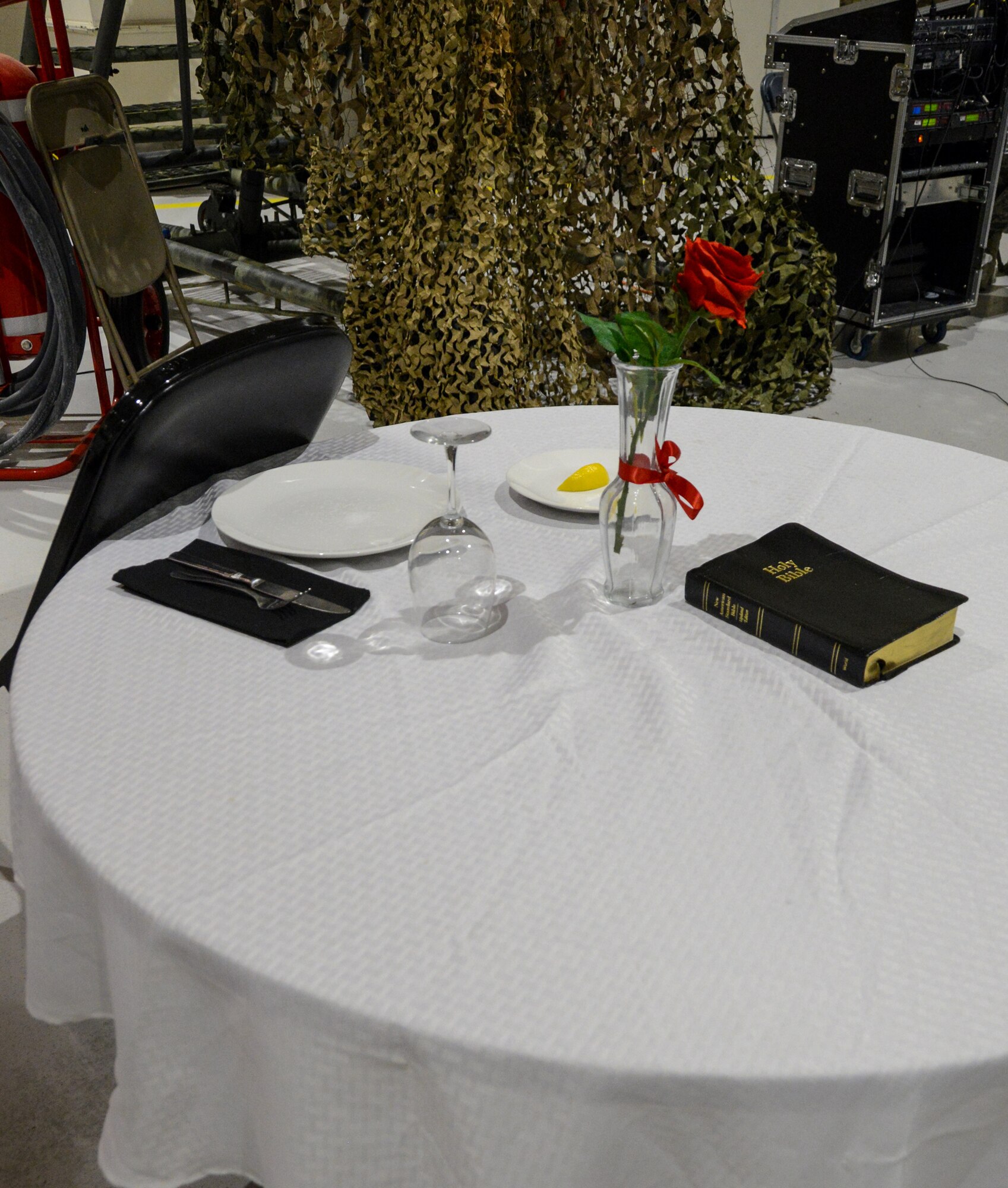 A table sits vacant in remembrance of Prisoners of War and Missing in Action. Included are an empty plate and glass, a lemon, a red rose, a Bible, and a chair in reservation.