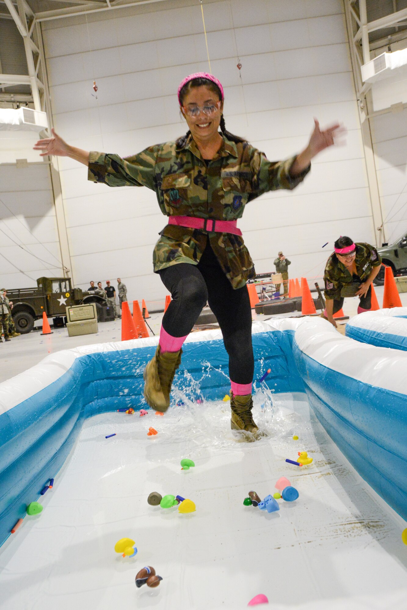 A Texas Air National Guard Airman runs through a pool of water and rubber duckies.