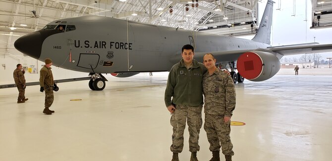 Captain matthew Saccone and Major Keremy Ketter pose in front of a KC-135 aircraft in a newly renovated hanager.