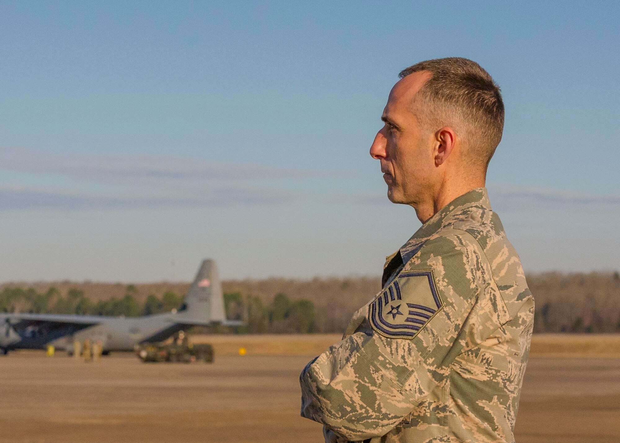 Master Sgt. Matthew Sheley poses on the flight line with C-130J aircraft in the background.
