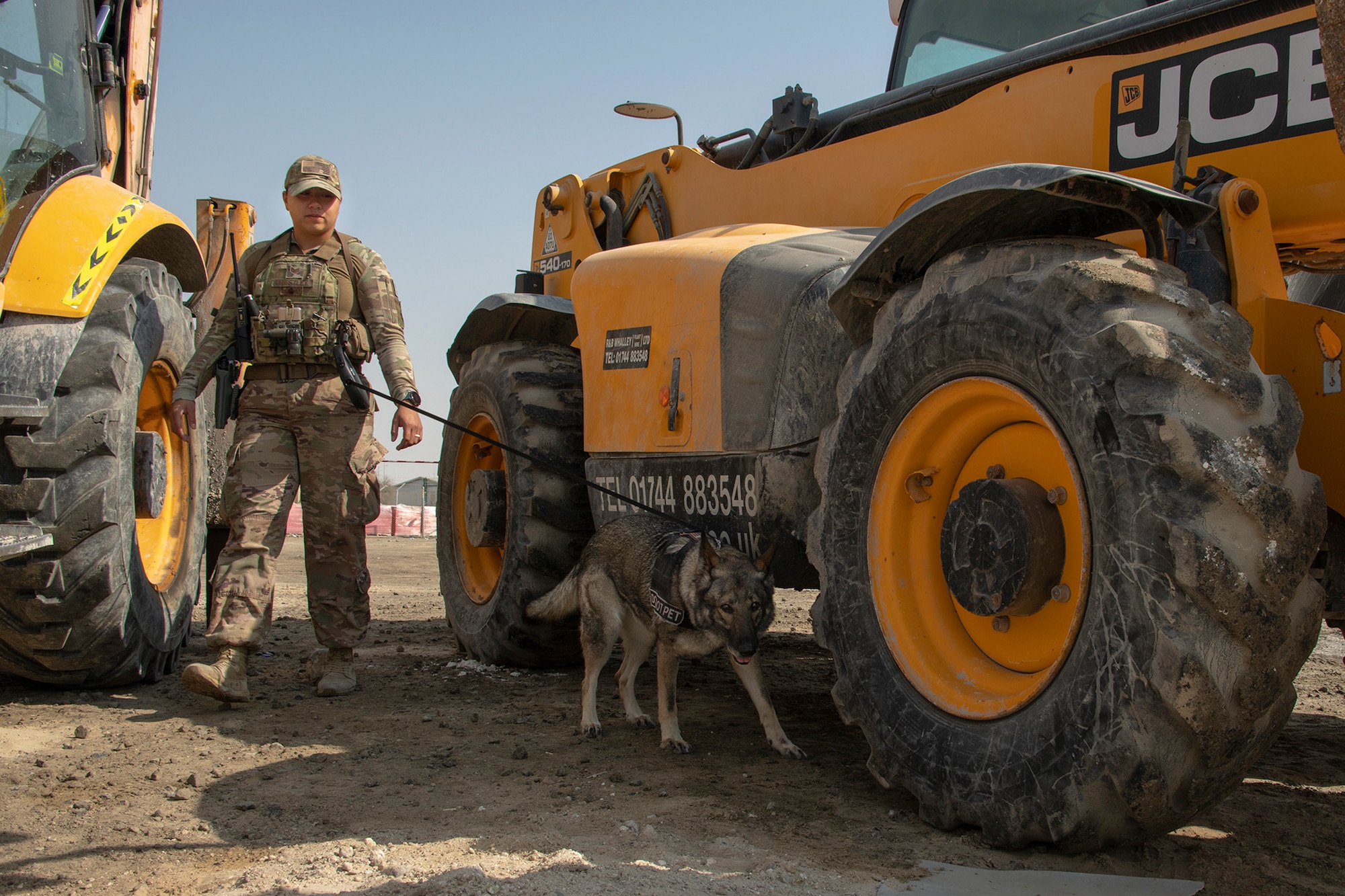 A military working dog handler searches a construction area for hidden substances