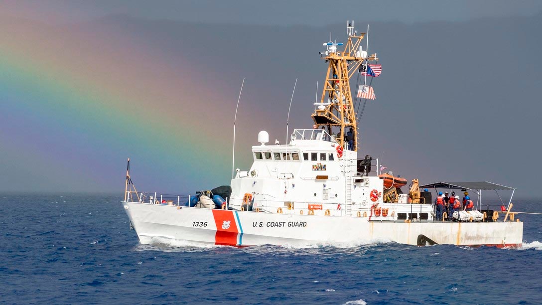 A U.S. Coast Guard boat on the water with a rainbow in the background