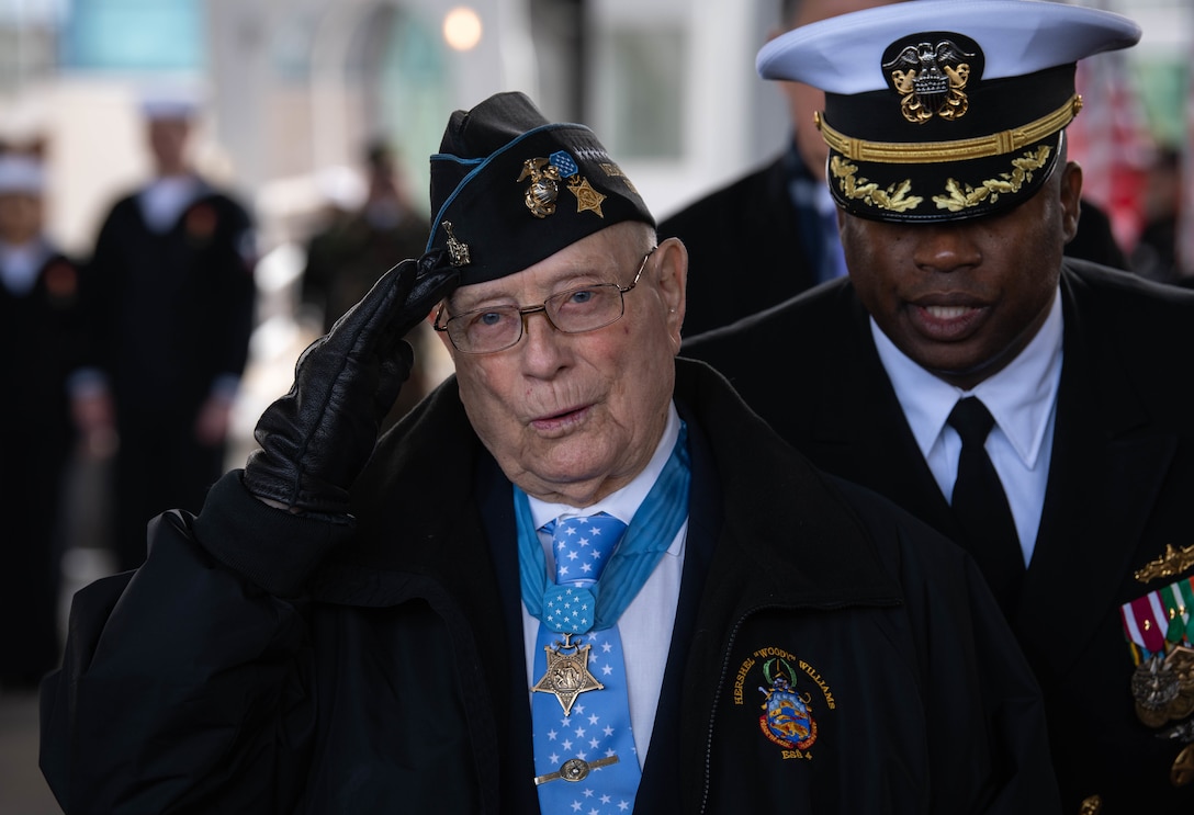 Hershel Woodrow Williams, Retired Chief Warrant Officer Four and Medal of Honor recipient, salutes as he is introduced to the stage along with other members of the ship commissioning committee, March 7.