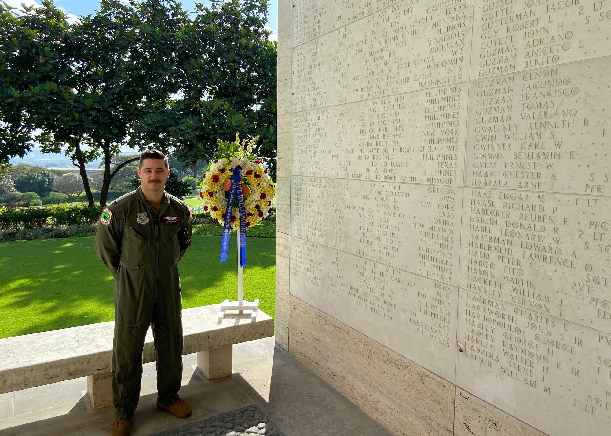 An Airman stands next to a wall with names on it.