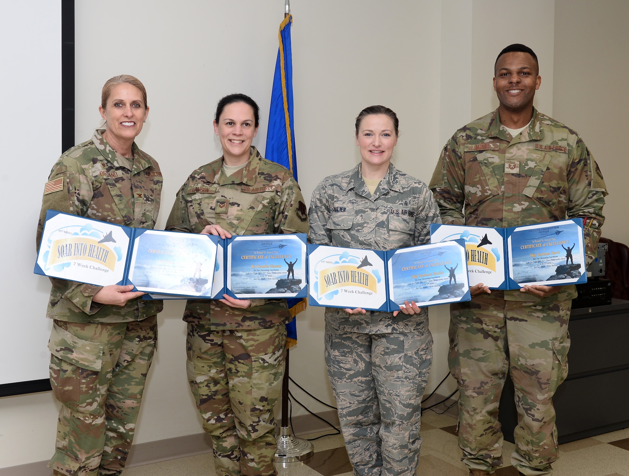 A picture of a woman awarding three people with certificates.
