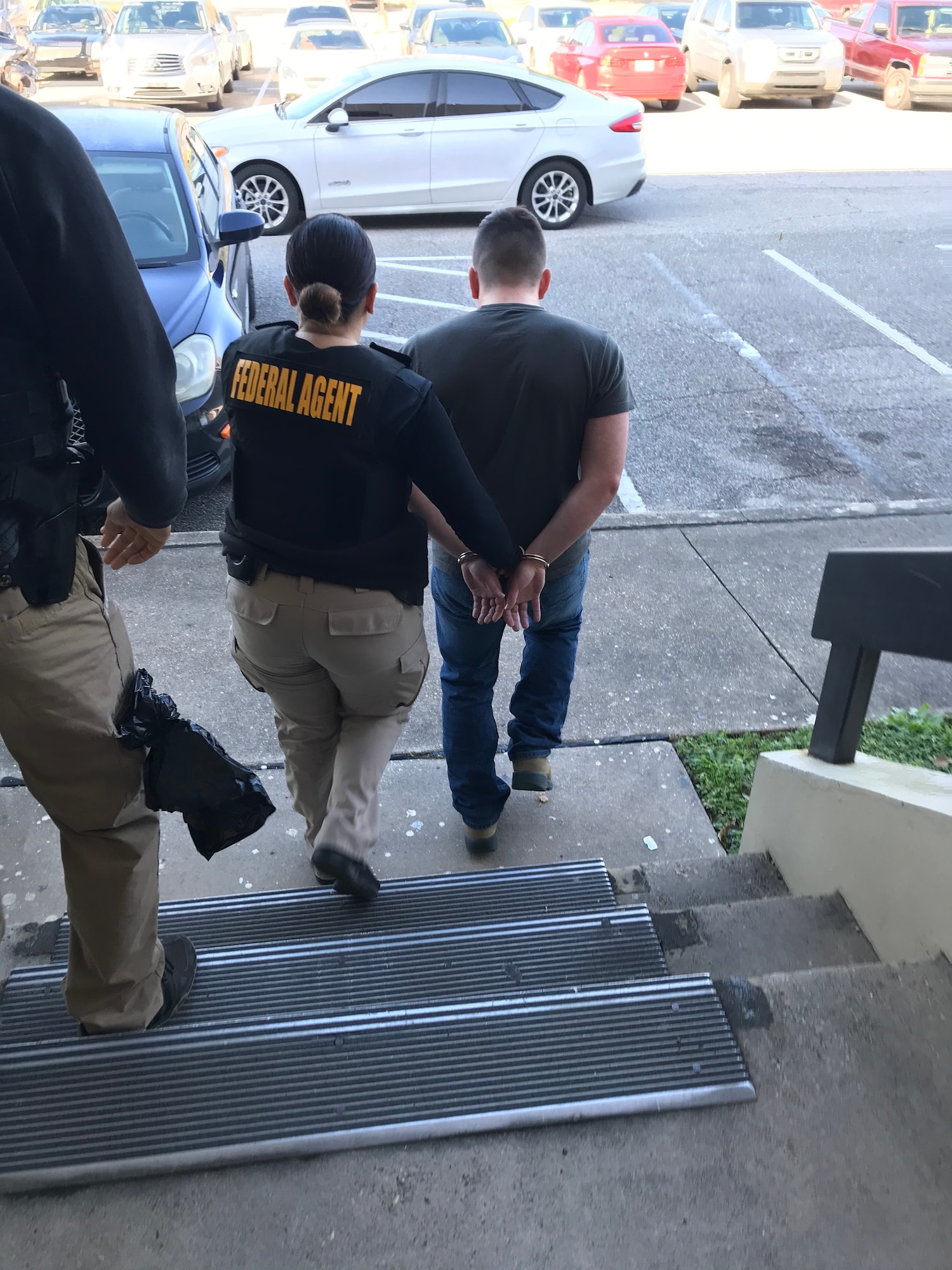 A Special Agent from Office of Special Investigations Detachment 407, Keesler Air Force Base, Miss., escorts an Airman charged with possession of child pornography to the base gate Feb. 24, 2020, where U.S. Marshals took him into custody and put him into confinement until prosecution. (Photo by OSI Det. 407)