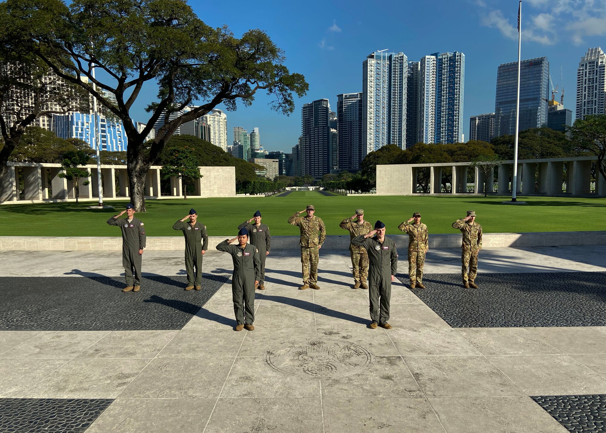 Airmen stand in a formation while saluting.