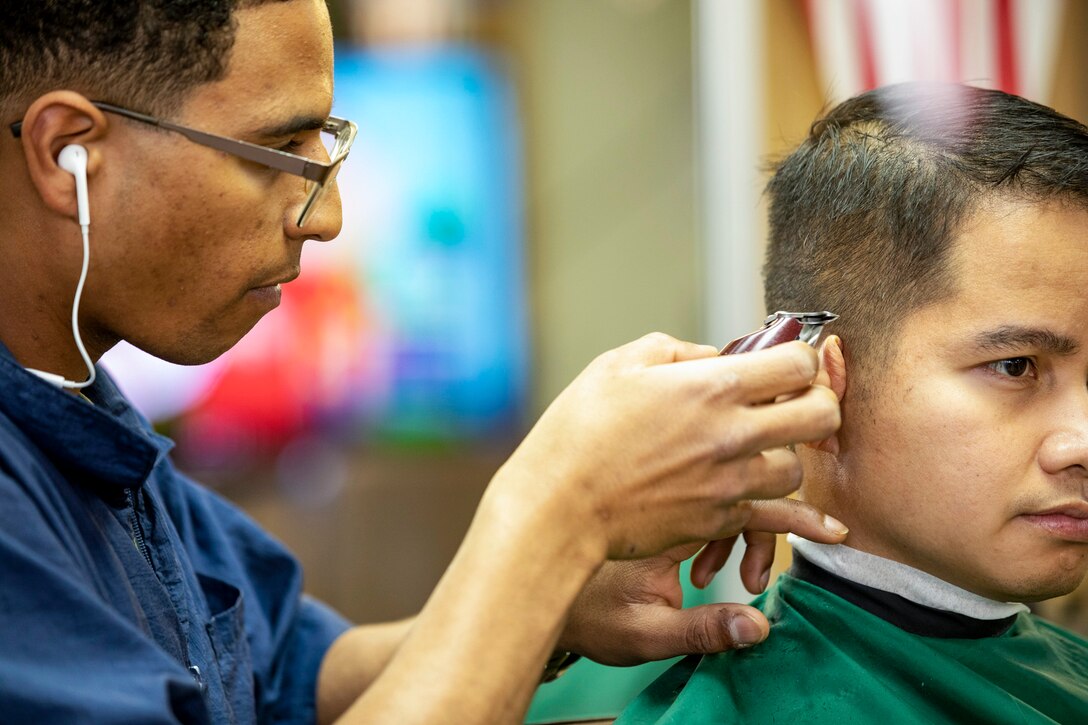 A Marine cuts another service member's hair.