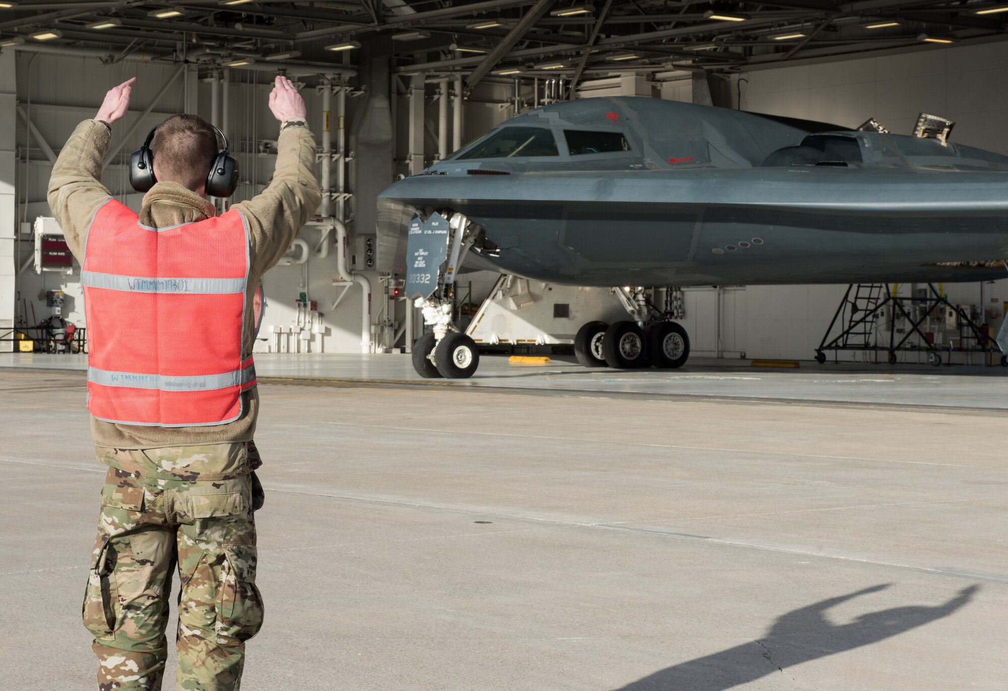 A crew chief assigned to the 131st Bomb Wing marshals a B-2 Spirit onto the flightline at Whiteman Air Force Base, Missouri, March 8, 2020. The B-2 is slated to support U.S. Strategic Command Bomber Task Force operations in Europe. These missions provide opportunities to train and work with our allies and partners in joint and coalition operations and exercises. (U.S. Air Force photo by Airman 1st Class Christina Carter)