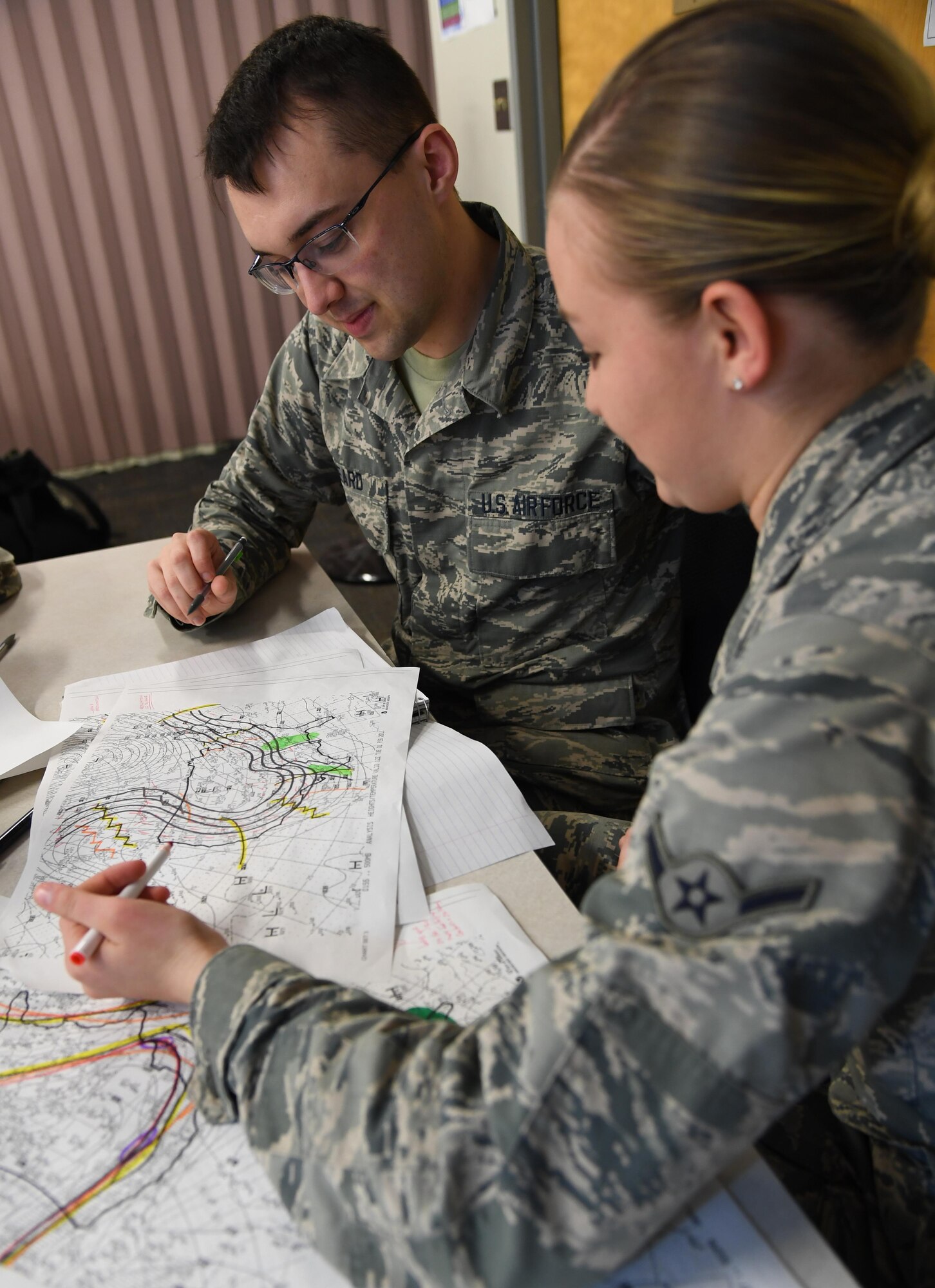 U.S. Air Force Airman 1st Class Brian Kineard and Airman Faith Jendrezjczyk, 335th Training Squadron students, plot data on weather charts used for training inside of the Joint Weather Training Facility at Keesler Air Force Base, Mississippi, Jan. 27, 2020. The weather apprentice course, which graduated 650 students this past year, takes 151 academic days to complete. Approximately 7,400 students go through the 335th TRS’s 13 Air Force Specialty Codes each year. (U.S. Air Force photo by Kemberly Groue)