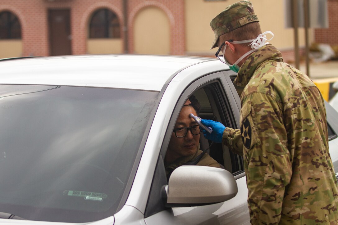 Soldier measures temperature of a driver entering post.