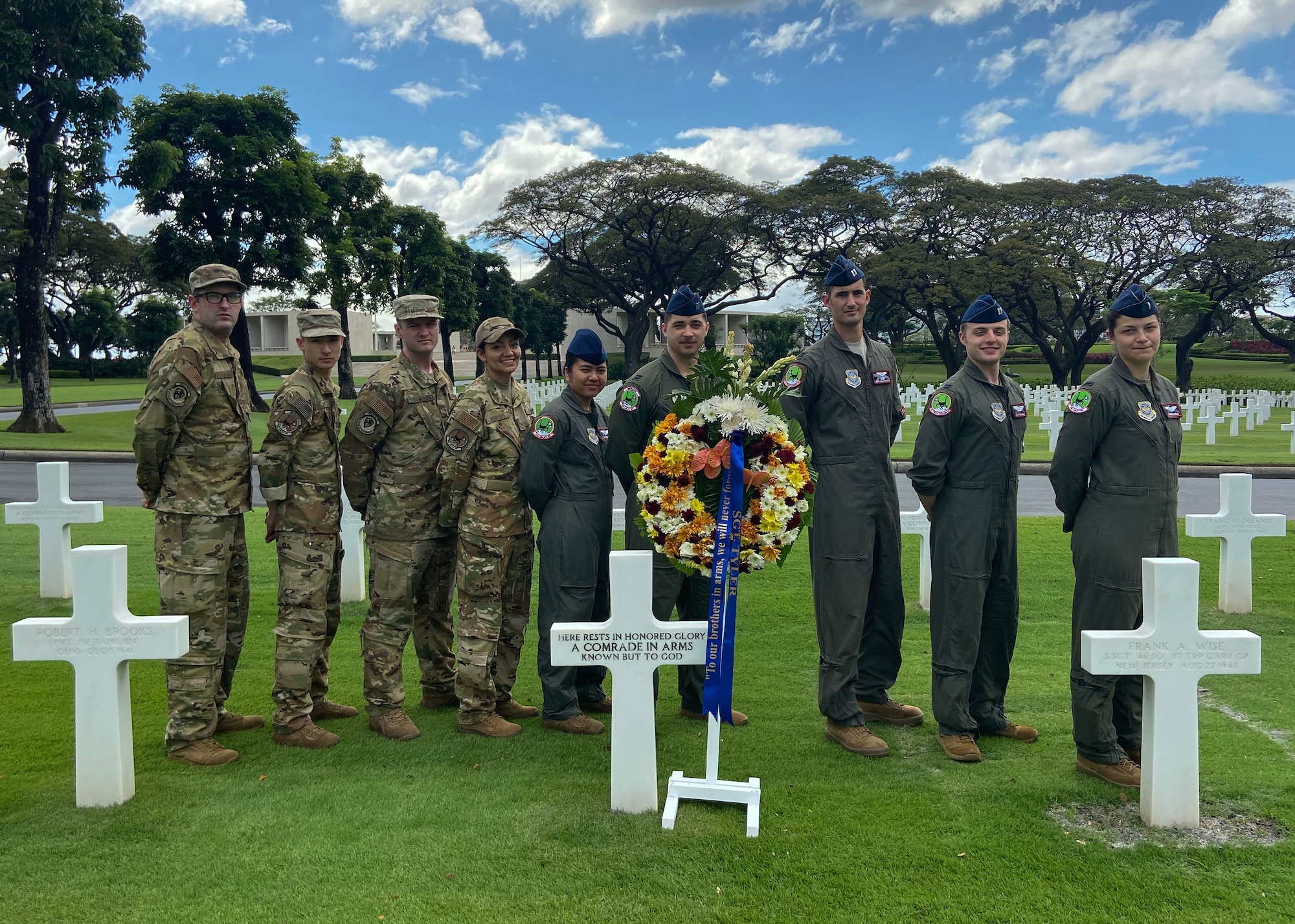 Airman stand in front of an unmarked gravestone.