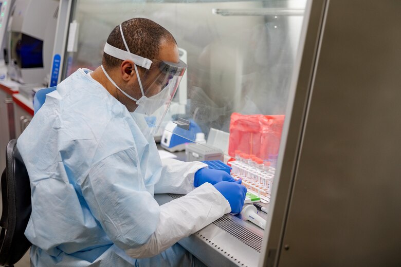 A man wearing a lab suit tests disease cells.