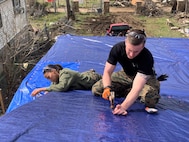 U.S. Marine Corps Sgt. Lakezia Ortiz, left, a recruiter from RSS Hendersonville and Capt. Kyle Cawthon, executive officer at RS Nashville, secure tarps on top of the roof of a damaged home in North Nashville, March 5, 2020. The Marines worked with local authorities and volunteers to assist with the clean-up and recovery efforts in the local area after severe storms and tornados blew across Middle Tennessee on March 3rd, 2020, which caused death, injury and widespread property damage. (U.S. Marine Corps photo by Sgt. Devin Phommachanh)