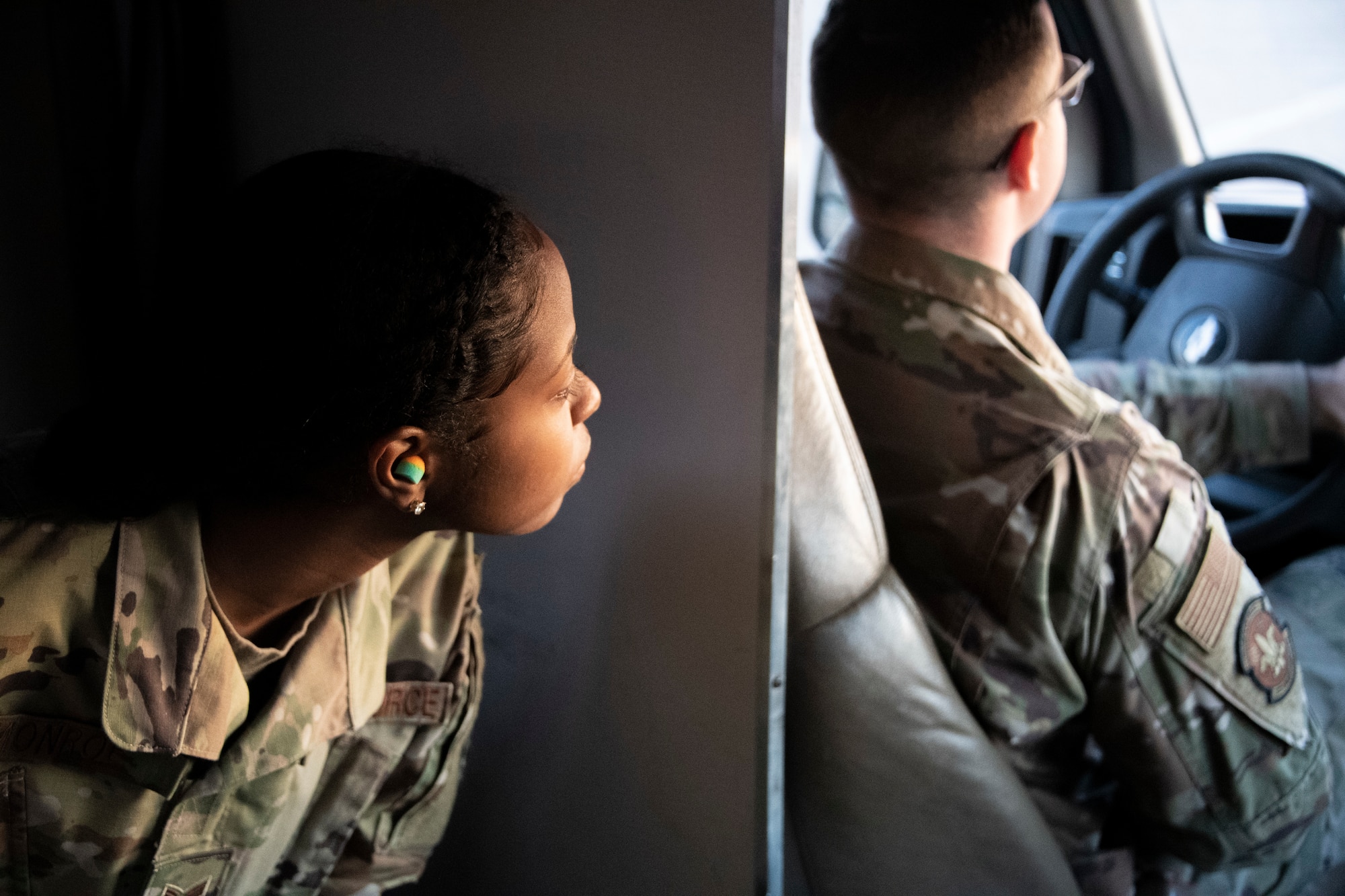 Photo of Airman looking out window of vehicle.