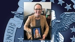 Woman with glasses, in brown blazer holds a framed picture of a young girl.