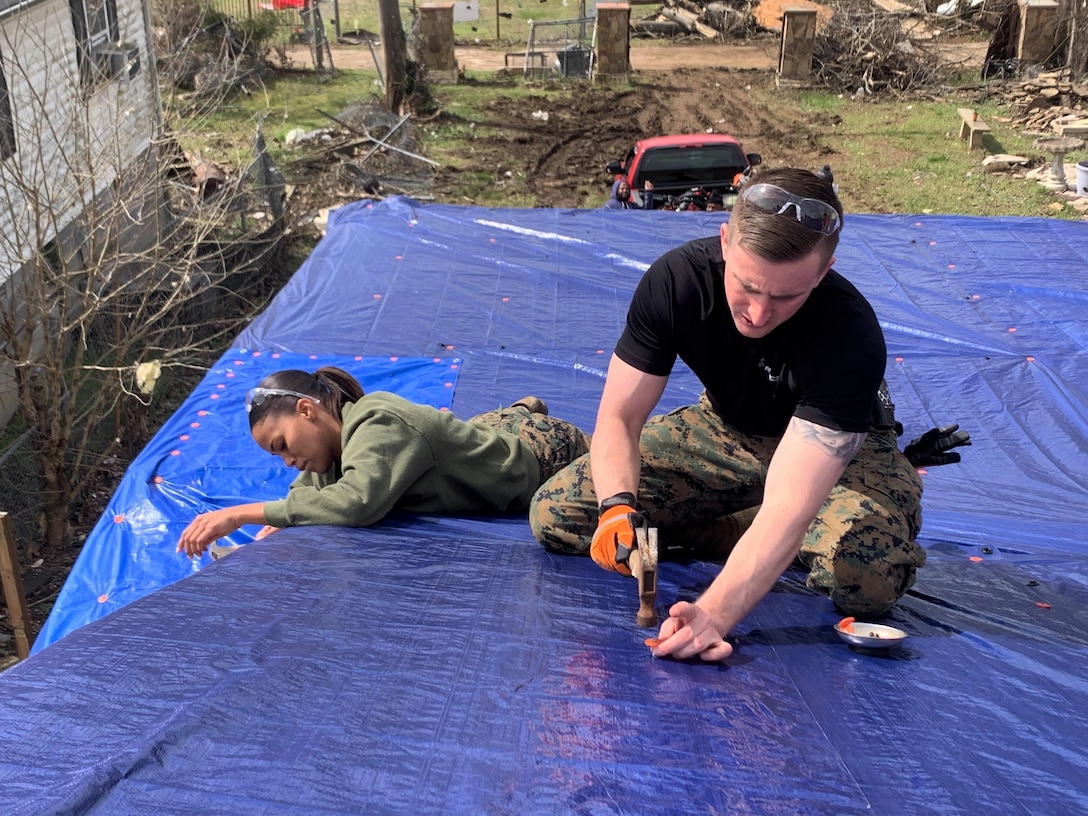 U.S. Marine Corps Sgt. Lakezia Ortiz, left, a recruiter from RSS Hendersonville and Capt. Kyle Cawthon, executive officer at RS Nashville, secure tarps on top of the roof of a damaged home in North Nashville, March 5, 2020. The Marines worked with local authorities and volunteers to assist with the clean-up and recovery efforts in the local area after severe storms and tornados blew across Middle Tennessee on March 3rd, 2020, which caused death, injury and widespread property damage. (U.S. Marine Corps photo by Sgt. Devin Phommachanh)