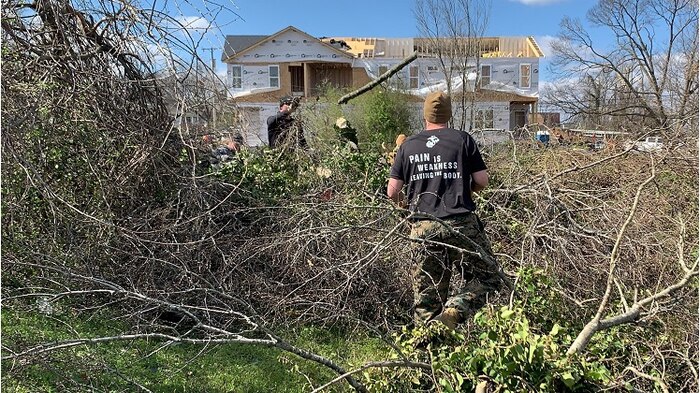 U.S. Marine Corps Gunnery Sgt. Johnny Reynolds, left, a pool program specialist from Recruiting Station Nashville, tosses a freshly cut tree branch to Gunnery Sgt. Matthew Coppersmith, the administrative chief at RS Nashville, as they work together to clear fallen trees and debris on March 6, 2020. The Marines worked with local authorities and volunteers to assist with the clean-up and recovery efforts in the local area after severe storms and tornados blew across Middle Tennessee on March 3rd, 2020, which caused death, injury and widespread property damage. (U.S. Marine Corps photo by Sgt. Devin Phommachanh)