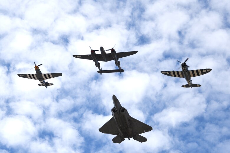 Photo of a U.S. Air Force F-22 Raptor flying in formation with a P-38 Lightning, P-47 Thunderbolt and a P-51 Mustang.