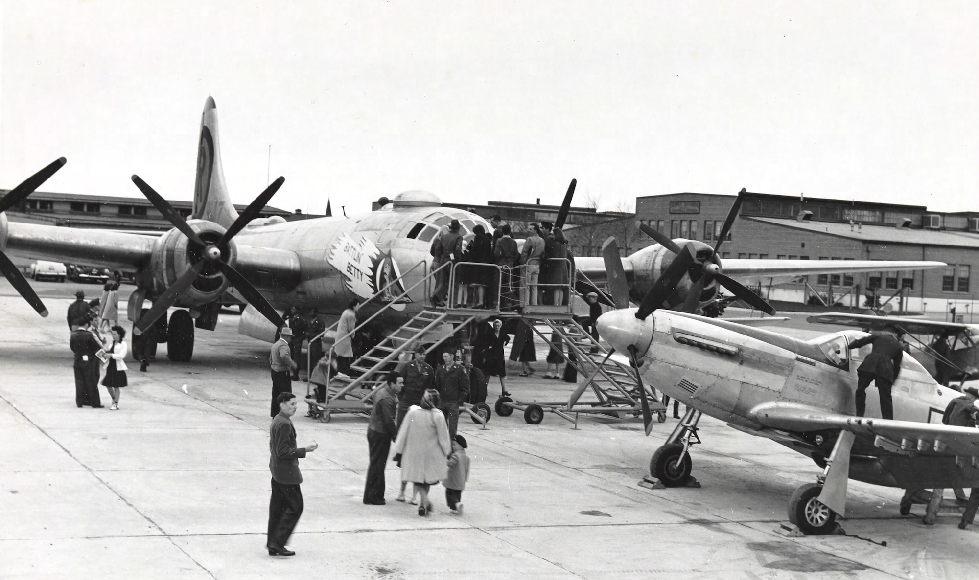 A dozen or more patrons admire static displays of aircraft on the  airfield.