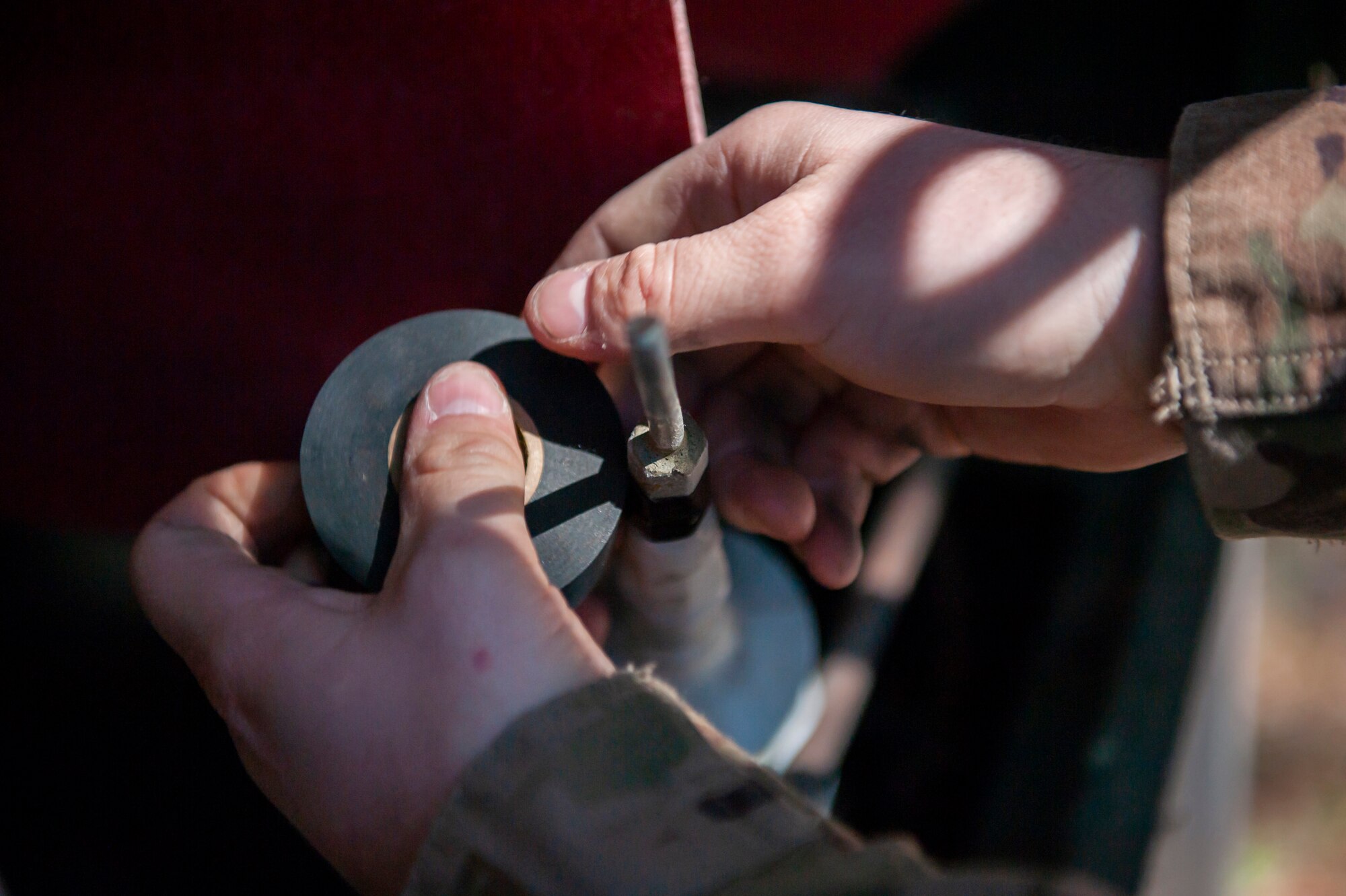 A photo of an Airman wrapping black tape around a wire