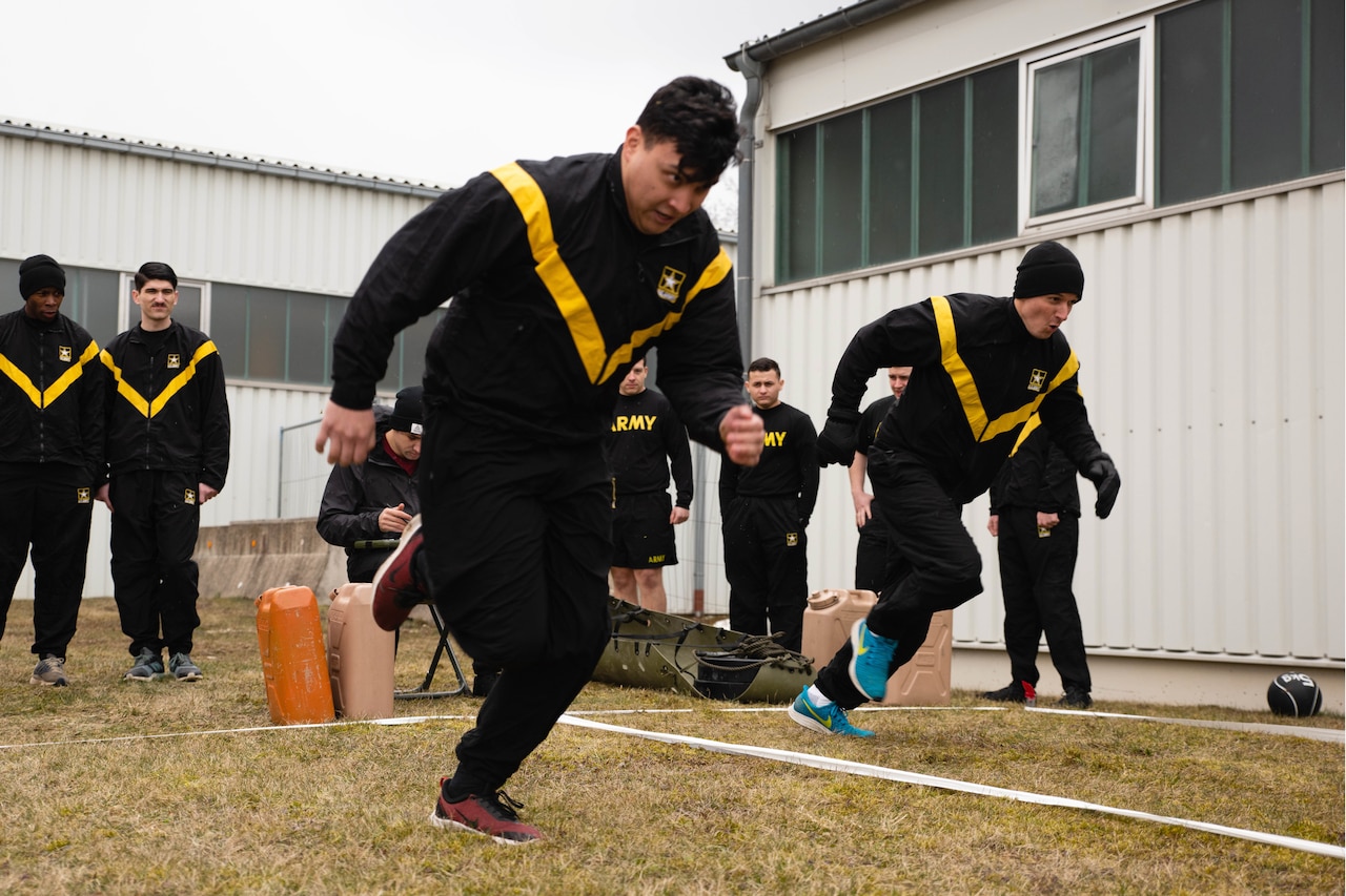 People dressed in black pants and long-sleeve shirts with a yellow “V” on top, race one another.