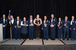 People stand on stage at an awards ceremony in a hotel.