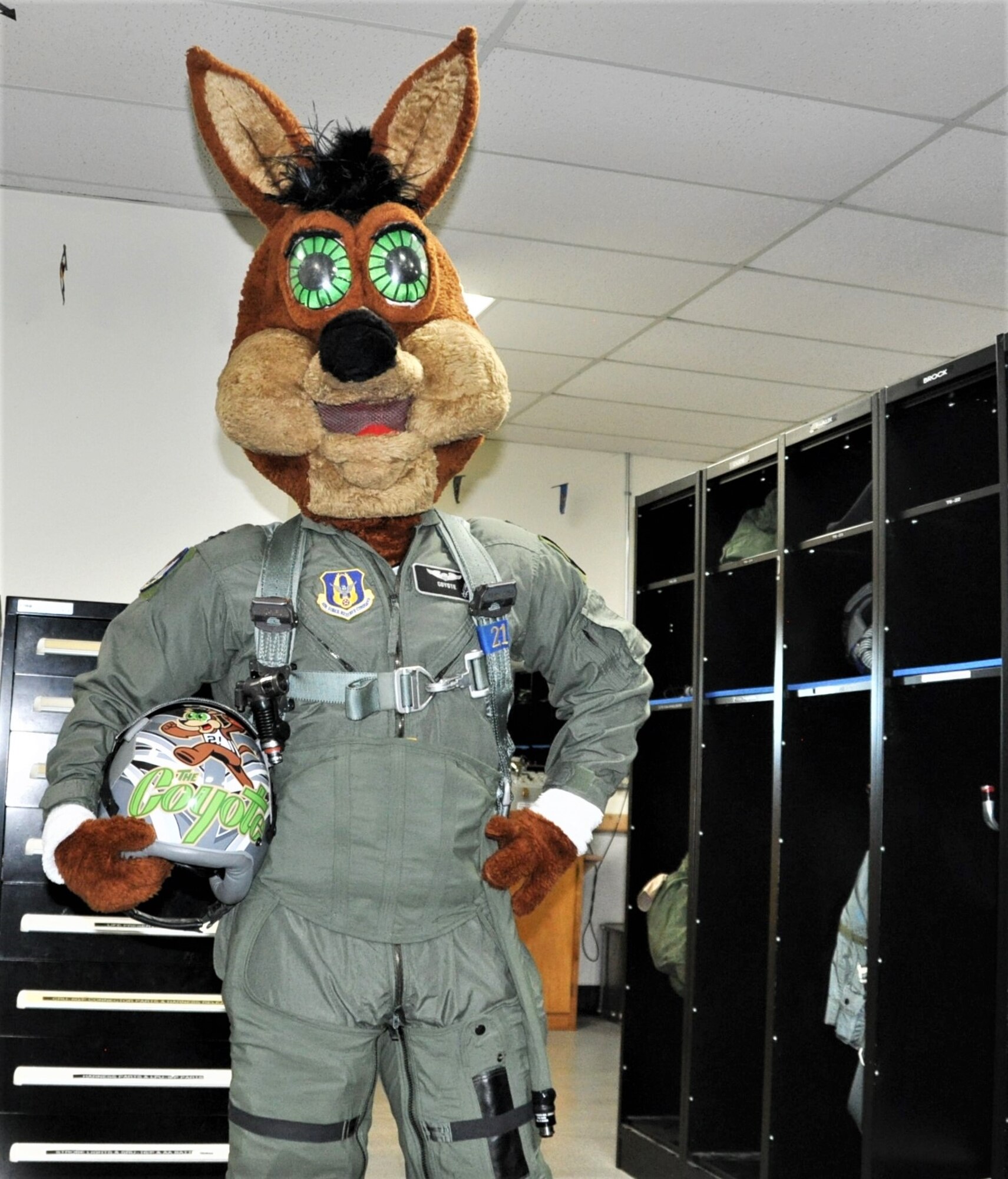 The Spurs Coyote poses with his customized helmet in the 559th Training Squadron locker room at Joint Base San Antonio-Randolph, Texas February 25 where Regular Air Force, Air Force Reserve, and civilian Airmen from the 340th Flying Training Group headquarters, 39th Flying Training Squadron T-6 Texan Flight, 12th Flying Training Wing Safety, 559th Flying Training Squadron T-6 team, and 3rd Combat Camera Squadron (JBSA-Lackland) members, and the NBA San Antonio Spurs production crew worked to put the Coyote through the pilot training process. Video footage will be used for a Spurs Military Appreciation video to be shown during the March 10 game.  (U.S. Air Force photo by Janis El Shabazz)