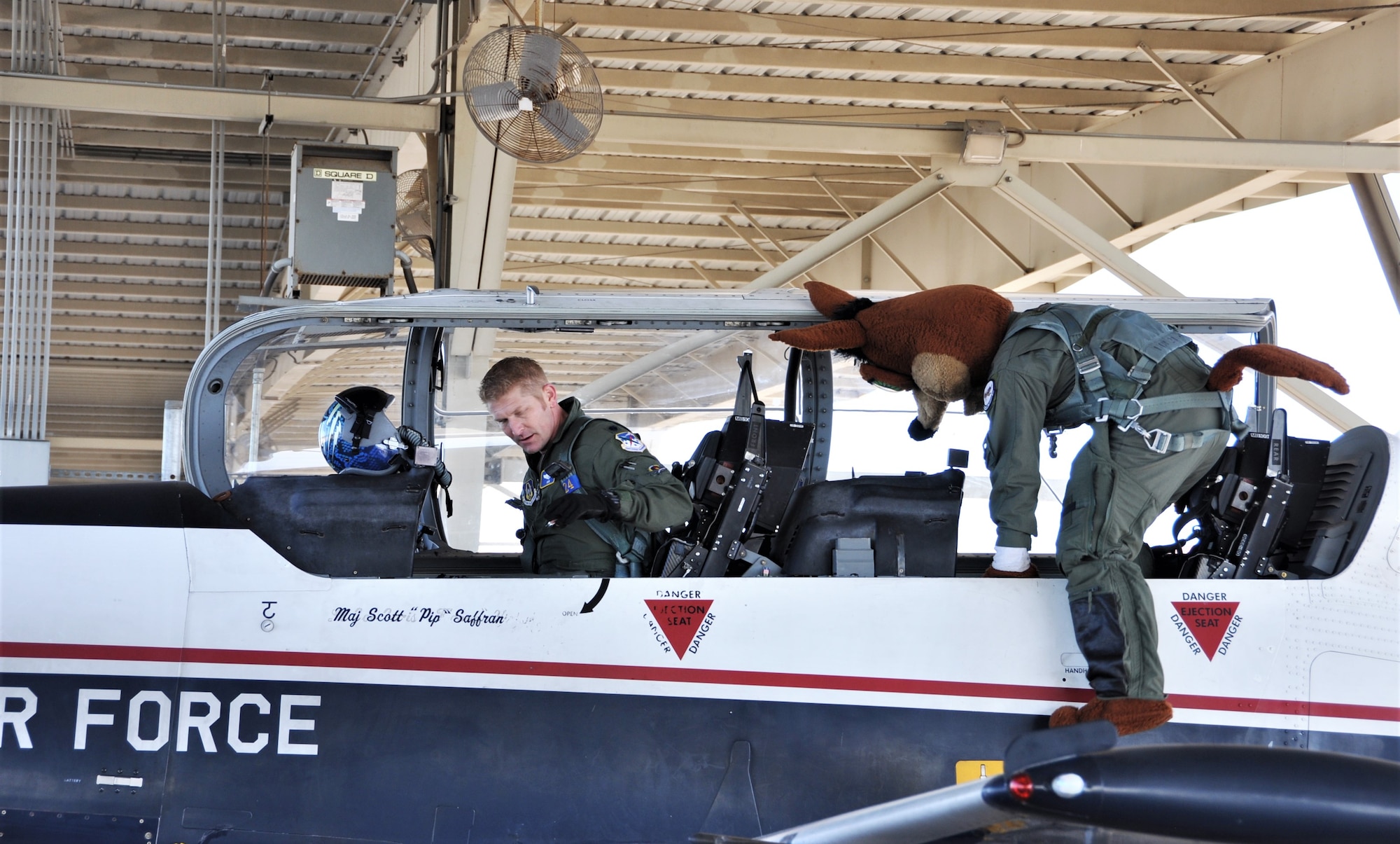The Spurs Coyote boards the aircraft for his simulated flight with his friend from the 340th Flying
 – Lt. Col. Mark Pasierb – at Joint Base San Antonio-Randolph, Texas February 25 where Regular Air Force, Air Force Reserve, and civilian Airmen from the 340th Flying Training Group headquarters, 39th Flying Training Squadron T-6 Texan Flight, 12th Flying Training Wing Safety, 559th Flying Training Squadron T-6 team, and 3rd Combat Camera Squadron (JBSA-Lackland) members, and the NBA San Antonio Spurs production crew worked to put the Coyote through the pilot training process. Video footage will be used for a Spurs Military Appreciation video to be shown during the March 10 game.  (U.S. Air Force photo by Janis El Shabazz)