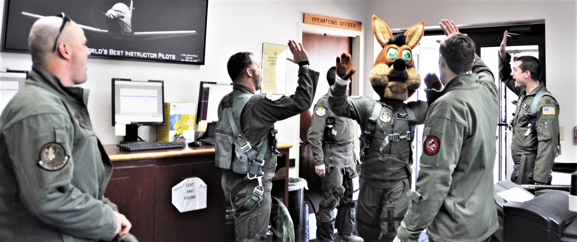 The Spurs Coyote gets high-fives all around February 25 in the 559th Training Squadron step room following his simulated flight at Joint Base San Antonio-Randolph, Texas where Regular Air Force, Air Force Reserve, and civilian Airmen from the 340th Flying Training Group headquarters, 39th Flying Training Squadron T-6 Texan Flight, 12th Flying Training Wing Safety, 559th Flying Training Squadron T-6 team, and 3rd Combat Camera Squadron (JBSA-Lackland) members, and the NBA San Antonio Spurs production crew worked to put the Coyote through the pilot training process. Video footage will be used for a Spurs Military Appreciation video to be shown during the March 10 game.  (U.S. Air Force photo by Janis El Shabazz)
