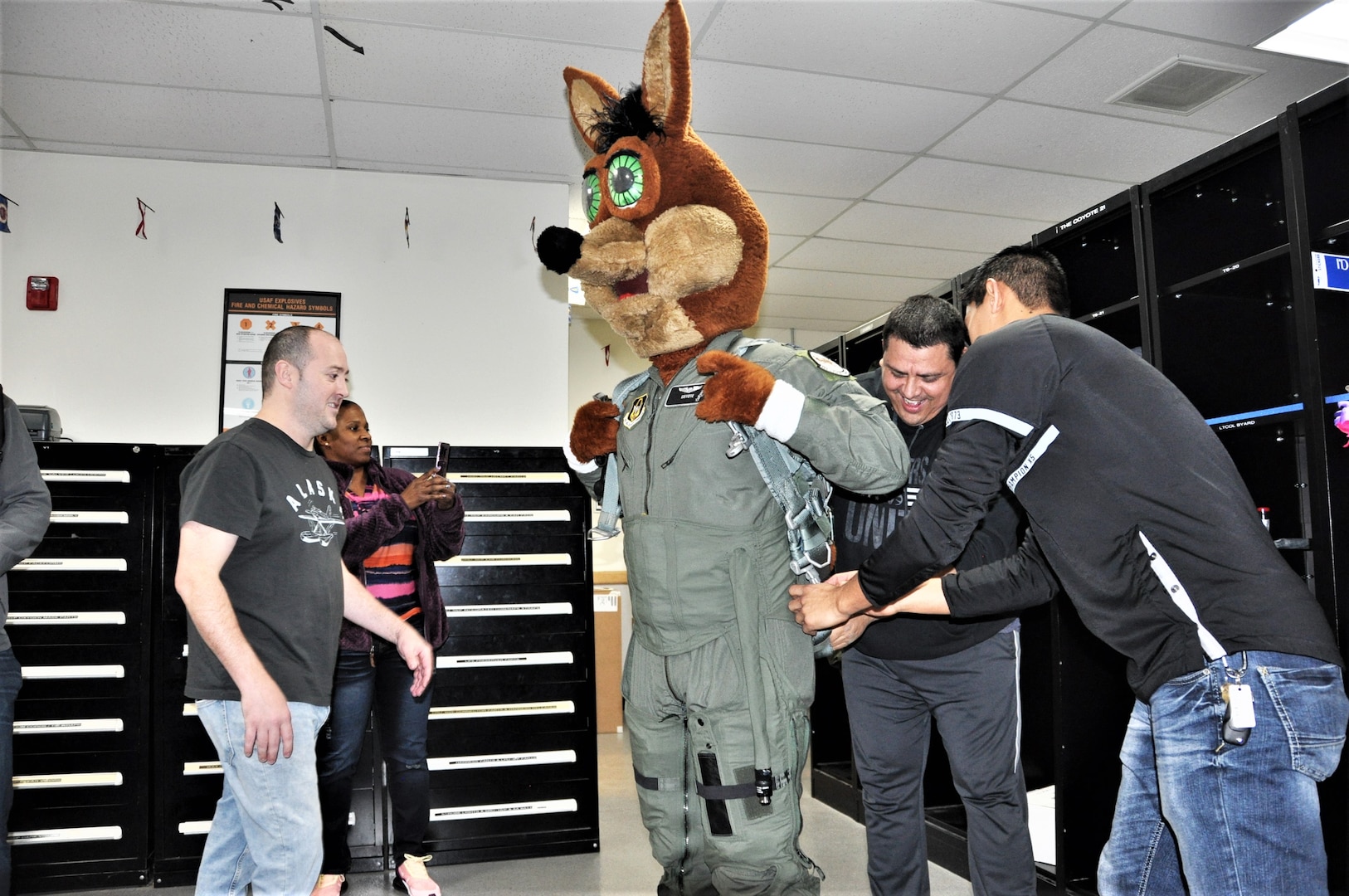 The Spurs Coyote gets fitted for his flight suit in the 559th Training Squadron locker room at Joint Base San Antonio-Randolph, Texas February 25 where Regular Air Force, Air Force Reserve, and civilian Airmen from the 340th Flying Training Group headquarters, 39th Flying Training Squadron T-6 Texan Flight, 12th Flying Training Wing Safety, 559th Flying Training Squadron T-6 team, and 3rd Combat Camera Squadron (JBSA-Lackland) members, and the NBA San Antonio Spurs production crew worked to put the Coyote through the pilot training process. Video footage will be used for a Spurs Military Appreciation video to be shown during the March 10 game. (U.S. Air Force photo by Janis El Shabazz)